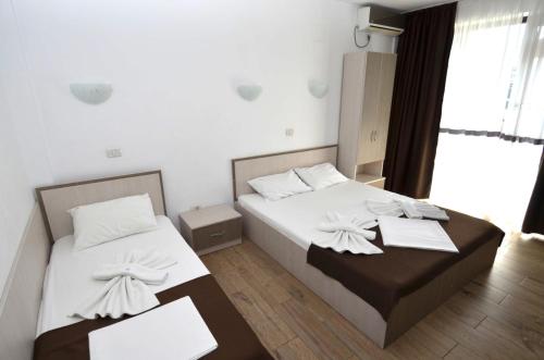 two beds in a room with white walls and wood floors at Vila Bliss in Costinesti