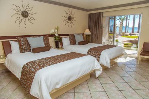 a hotel room with two beds and a balcony at Estero Beach Hotel & Resort in Ensenada