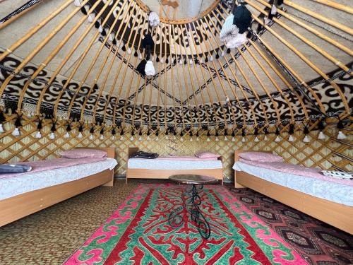 a room with two beds and a table in a yurt at Guest house and yurt camp Svetlana in Bokonbayevo