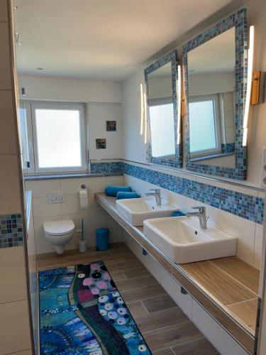Un baño con dos lavabos y un inodoro y espejos. en Ferienwohnung am Bienenhaus, en Salem