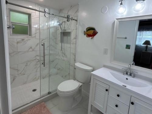 a bathroom with a shower and a toilet and a sink at My Beach Key - Waterfront Home, 32' Dock, Tiki Hut, Beach Club Access w Pool in Key Colony Beach