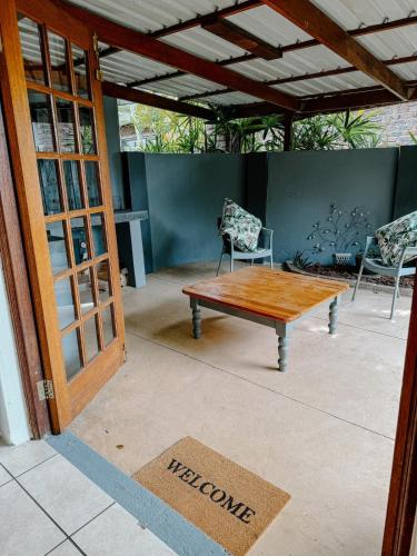 a patio with a wooden table and two chairs at The Garden Den in Nelspruit