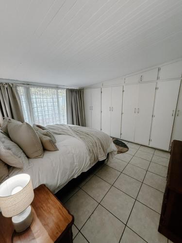 a bedroom with a bed with white cabinets and a window at The Garden Den in Nelspruit