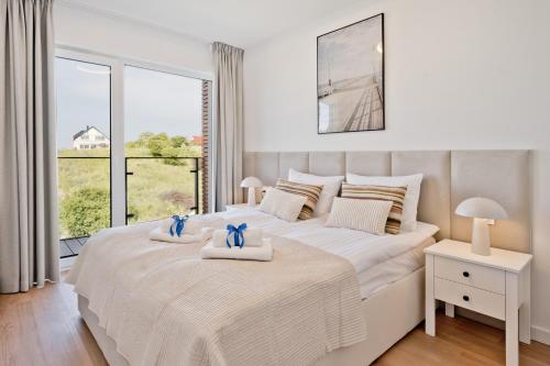 a white bedroom with a large bed with two towels at Aparthotel Anchoria BlueApart in Mechelinki
