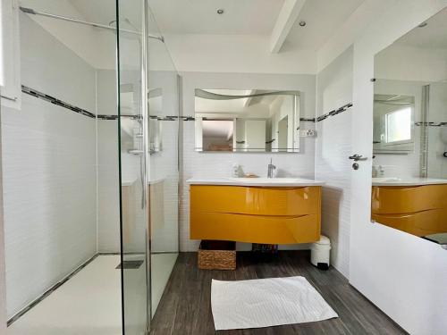 La salle de bains est pourvue d'un lavabo jaune et d'une douche en verre. dans l'établissement Villa La Pignotte 2 min de la plage, à Gujan-Mestras