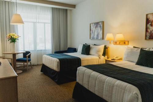 a hotel room with two beds and a table at Hotel San Marcos Grand in Culiacán