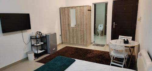 a room with a bathroom with a toilet and a television at Muscat Airport Guesthouse All Private Ensuite Rooms in Muscat