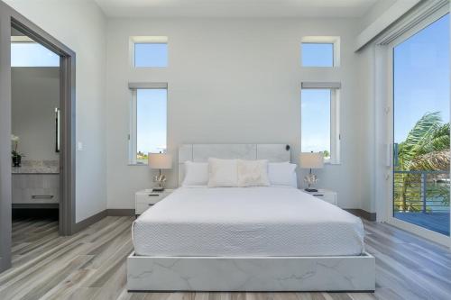 a white bedroom with a large bed and windows at Off the Hook - Luxury Waterfront Pool Home, Kayaks & Bikes, 30' Dock in Marathon
