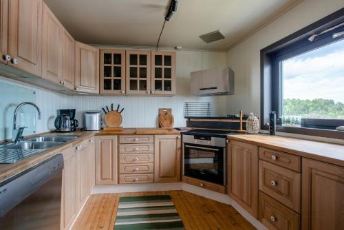 a kitchen with wooden cabinets and a large window at Sea View And Idyll In Charming Island Cabin in Brevik