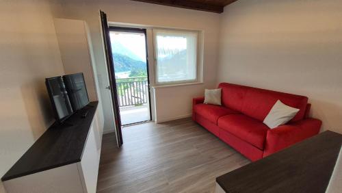 a living room with a red couch and a television at Alps lodge in Domegge di Cadore