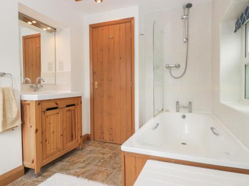 ein Badezimmer mit Badewanne, Waschbecken und Dusche in der Unterkunft Wren Cottage in Ross on Wye