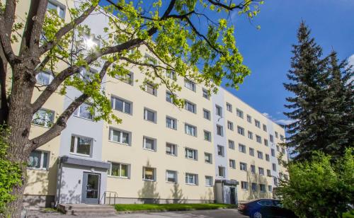 ein weißes Gebäude mit einem Baum davor in der Unterkunft Aardla Cozy Apartment in Tartu