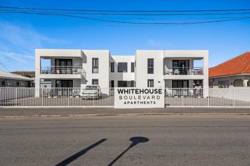 a white building with a sign on the side of the street at The Whitehouse Boulevard Apartments in Willemstad