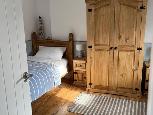 a bedroom with a bed and a wooden cabinet at Still Waters in Brixham