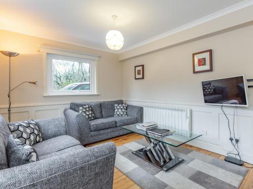 a living room with two couches and a tv at Chesnut Cottage in Banavie