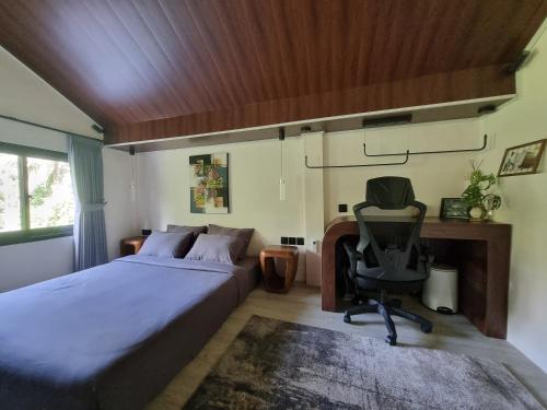 a bedroom with a bed and a desk and a chair at Happy Spiritus Guethouse Tabanan in Tabanan