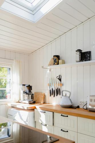 a kitchen with white cabinets and a skylight at Cottage Life In Intimate Wooden Cabin in Dronningmølle