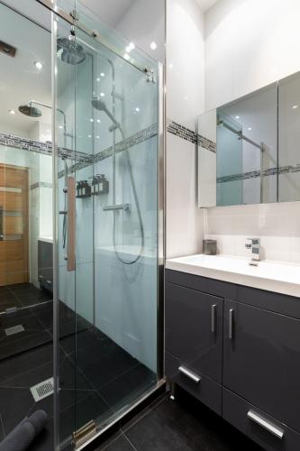 une salle de bain avec une douche en verre et un lavabo dans l'établissement Le Miramar Apartment Sea View, à Cannes