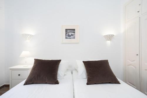 a white bedroom with a white bed with two brown pillows at Romantic Retreat in Prime Position in Acantilado de los Gigantes