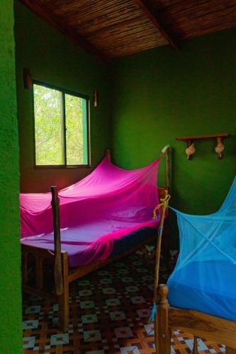 a bedroom with a bed with pink sheets and a window at Jardin Secreto in El Viejo
