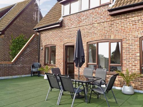 a patio with a table and chairs and an umbrella at Pine View - E5473 in Cromer