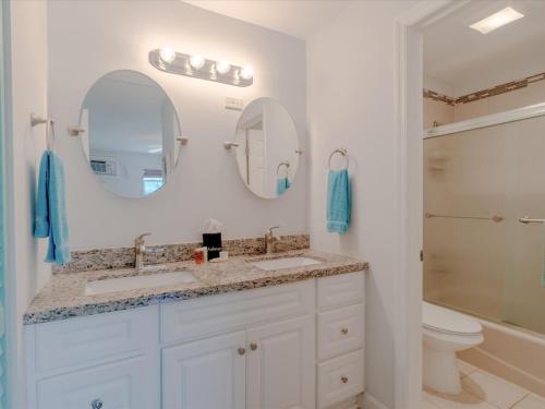 a bathroom with two sinks and two mirrors at Sanctuary Bay - Private Waterfront Home, 42' Dock in Marathon