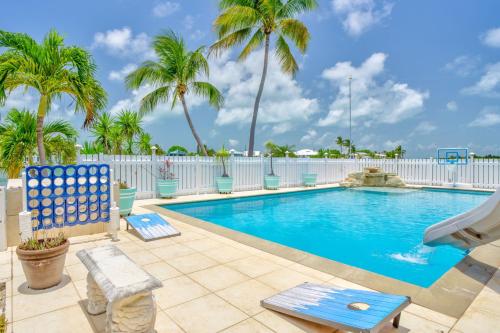 a swimming pool with palm trees and a white fence at Sailfish Point - Luxury Waterfront Pool Home, 80' Dock in Key Colony Beach