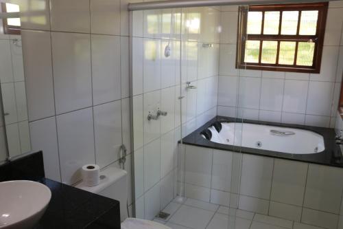 a bathroom with a tub and a toilet and a sink at Pousada Alto do Bau in Conceição do Mato Dentro