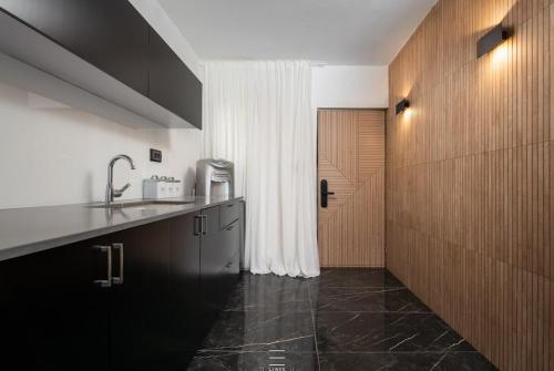 a kitchen with black cabinets and a white curtain at Mini paradise with Jacuzzi shelter in the building in Qiryat Motzkin