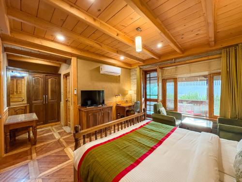 a bedroom with a large bed and a television at Shivadya - A Luxury Boutique Experience in Manāli