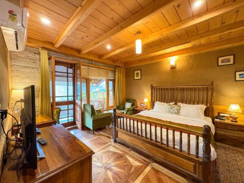 a bedroom with a bed and a desk and a television at Shivadya - A Luxury Boutique Experience in Manāli