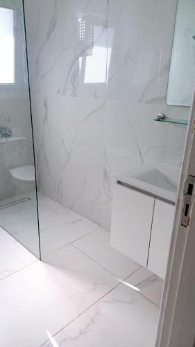 a white bathroom with a shower and a sink at Modern 2bd appartment near mall- Internet 1Gbps in Paphos