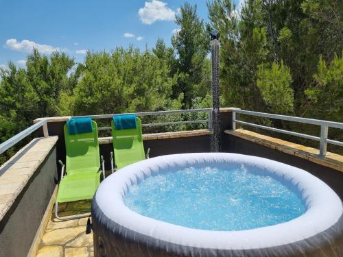 a hot tub on a deck with two lawn chairs at Villa Panorama in Pridraga