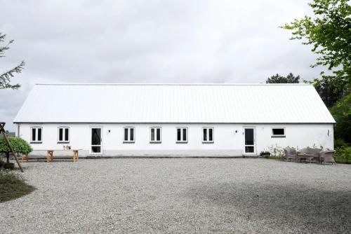 a white barn with a white roof at Renovated Estate With Private Beach in Roslev