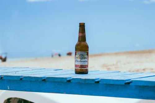 a bottle of beer sitting on a picnic table on the beach at Pousada Brésil Aventure in Galinhos