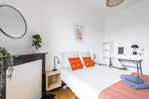 - une chambre avec un lit doté d'oreillers orange et d'un miroir dans l'établissement Le cosy - charmant 2 chambres - centre, à Reims