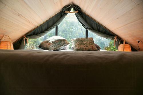 une tente avec deux oreillers en face d'une fenêtre dans l'établissement Treehouse Lodge In The Dentelles De Montmirail, à Lafare
