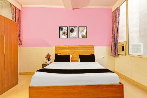 a bedroom with a large bed with pink walls at Super Hotel O Kanode Gate Formerly Hotel Dhruv in Rewāri