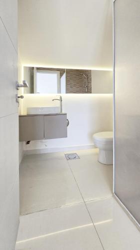 a white bathroom with a sink and a toilet at Tabarja Hills apartment in ‘Ayn aş Şughayrah