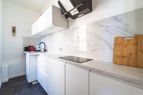 - une cuisine blanche avec des placards blancs et un comptoir dans l'établissement Le cosy - charmant 2 chambres - centre, à Reims