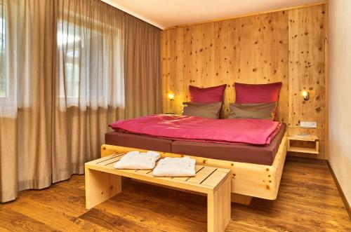 - une chambre avec un grand lit et un mur en bois dans l'établissement Stern Romantik am Hof, à Kollnburg