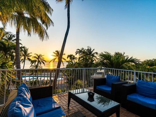 a balcony with blue chairs and a table and palm trees at Sunsets in Paradise - Private Direct Waterfront Pool Home, 22' Dock in Marathon