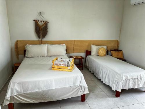 a bedroom with two beds with white sheets at Pousada Flor dos Buritis in Paulino Neves