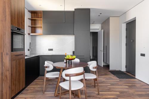 a kitchen with a wooden table and white chairs at Апартаменты с двумя спальнями и собственной террасой на крыше в доме с бассейном, возле пляжа Яз in Budva