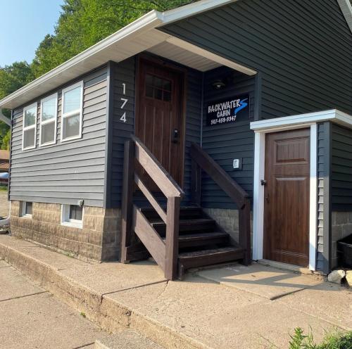 a blue house with a wooden door and stairs at Dragonfly Nest, cabin vibe, river views in Fountain City