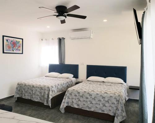 a bedroom with two beds and a ceiling fan at Casa Aura in Isla Mujeres
