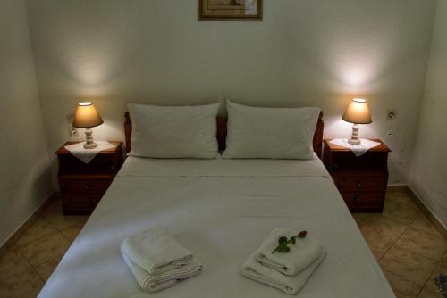 a bedroom with a bed with towels and two lamps at Λευκή Καμέλια in Anilio Pelion