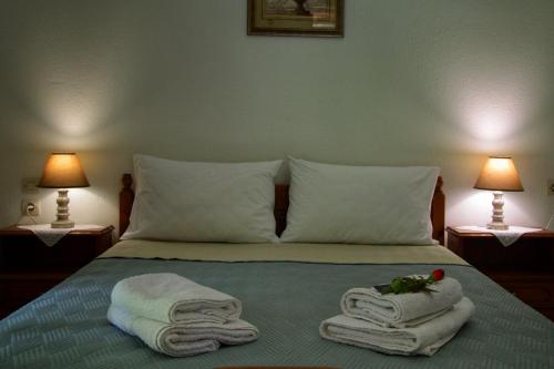 a bedroom with a bed with towels and two lamps at Λευκή Καμέλια in Anilio Pelion