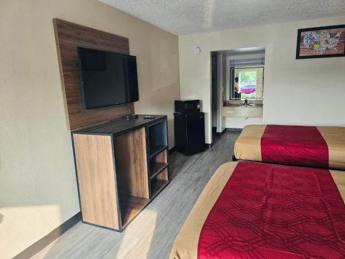 a hotel room with a bed and a flat screen tv at Studios 4 Less Chesapeake in Chesapeake