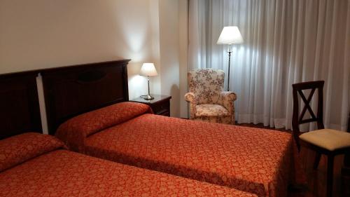 a hotel room with two beds and a chair at Apartamentos Maritimo Suites-Solo Adultos in O Grove